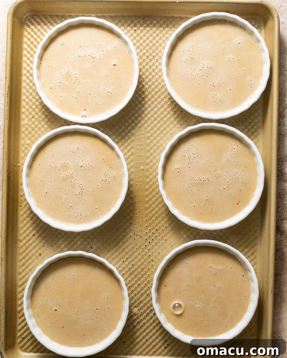 custard divided into 6 ramekins on a baking sheet.