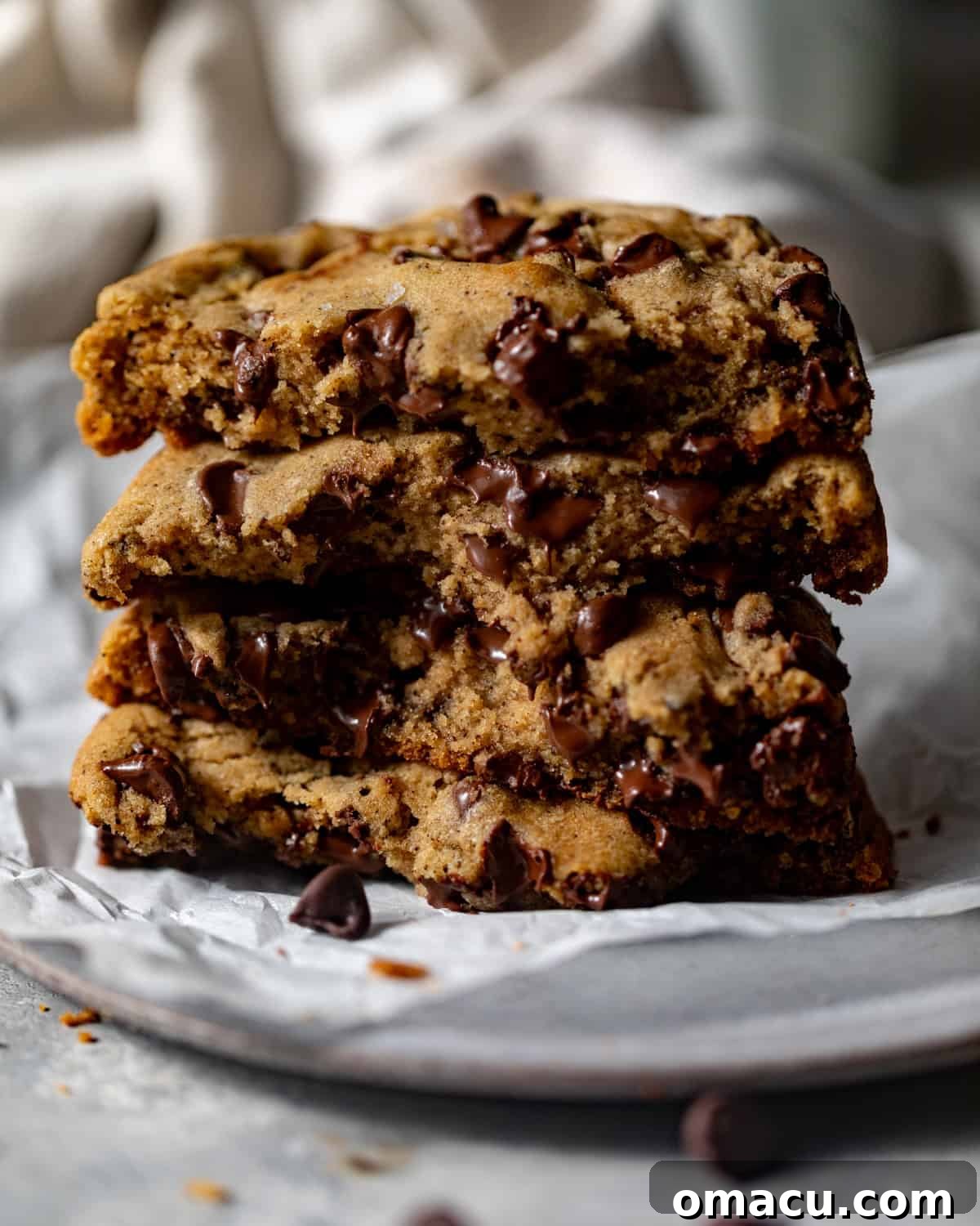 A delectable stack of golden brown butter chocolate chip cookies on a white plate, highlighting their rich color and inviting texture.