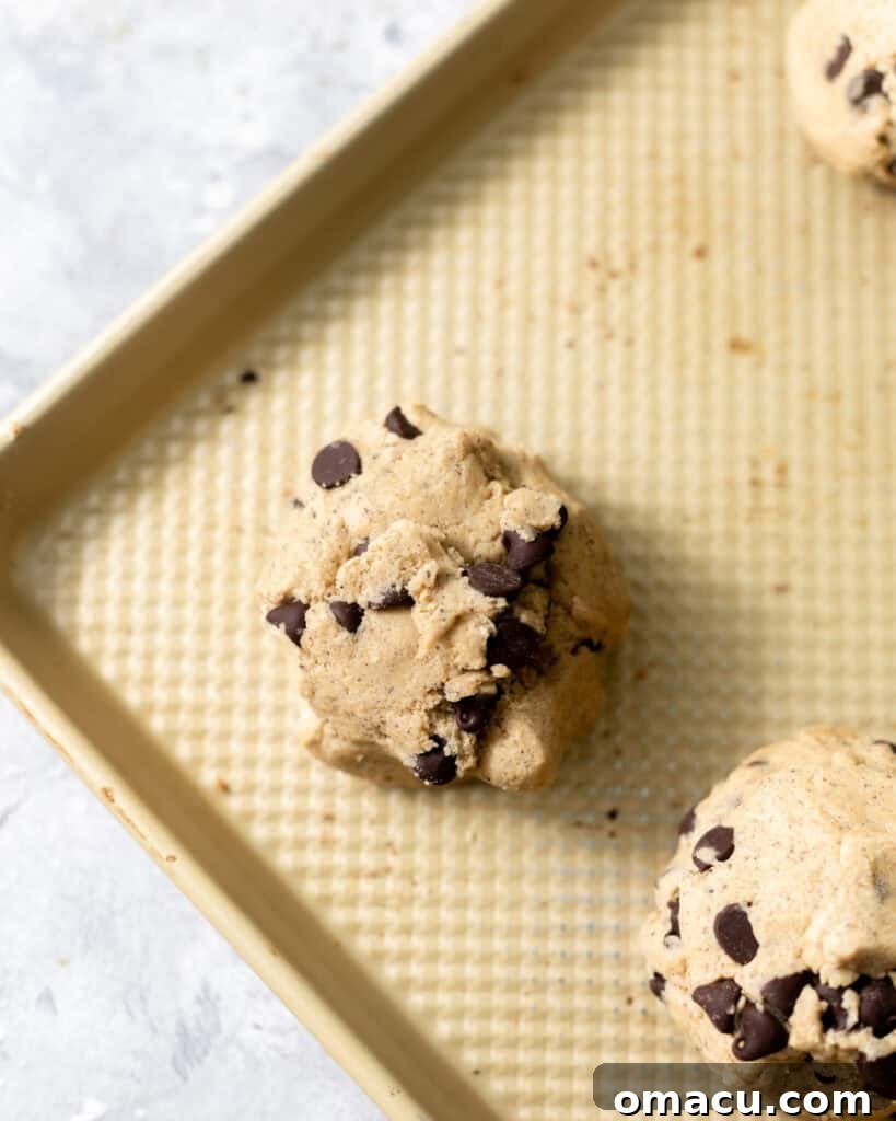 Portioned cookie dough balls arranged on a parchment-lined baking sheet, ready for chilling before baking.