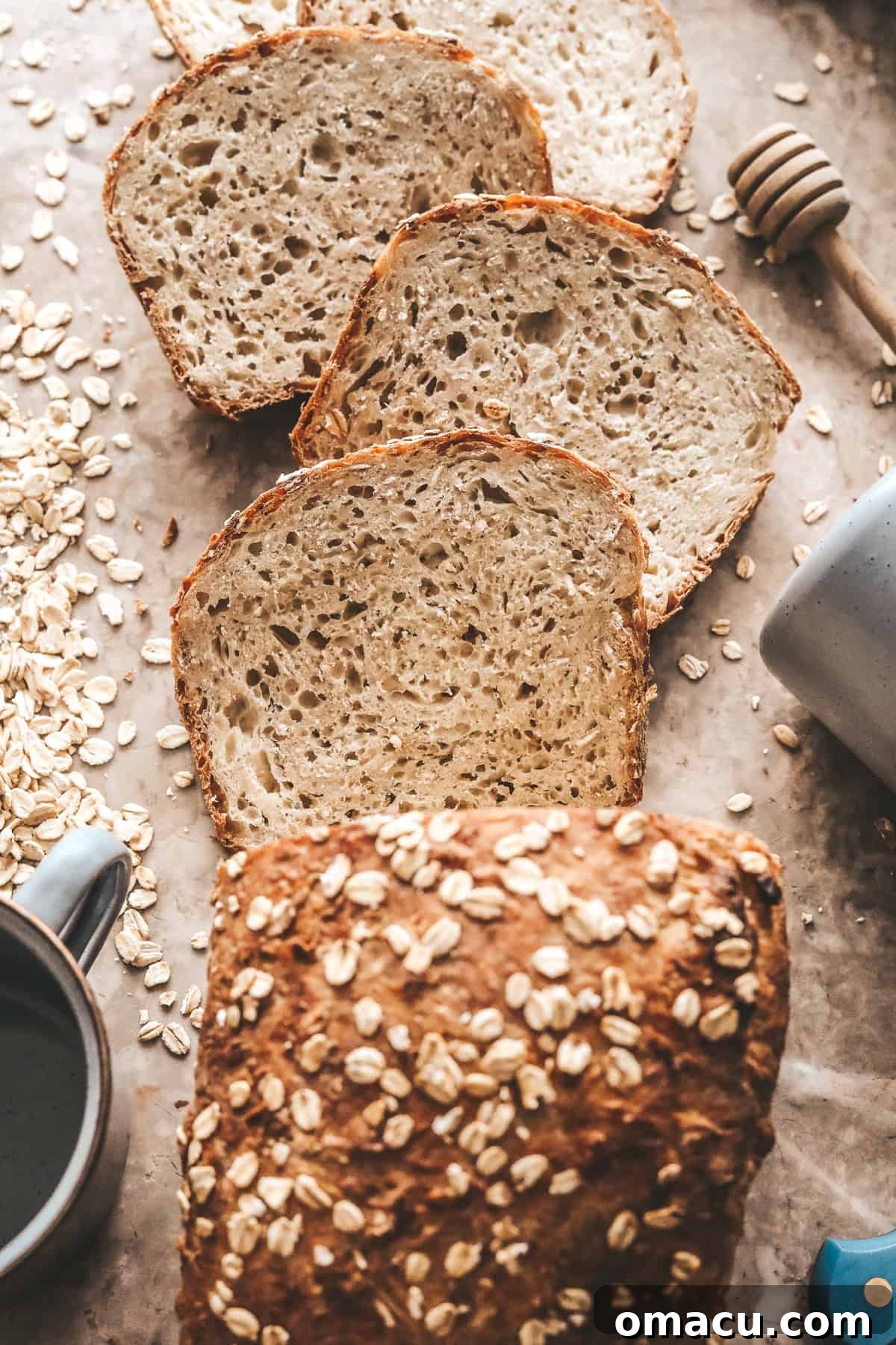 Sliced Honey Oat Bread with oats sprinkled on top and a honey dipper, emphasizing its wholesome ingredients.