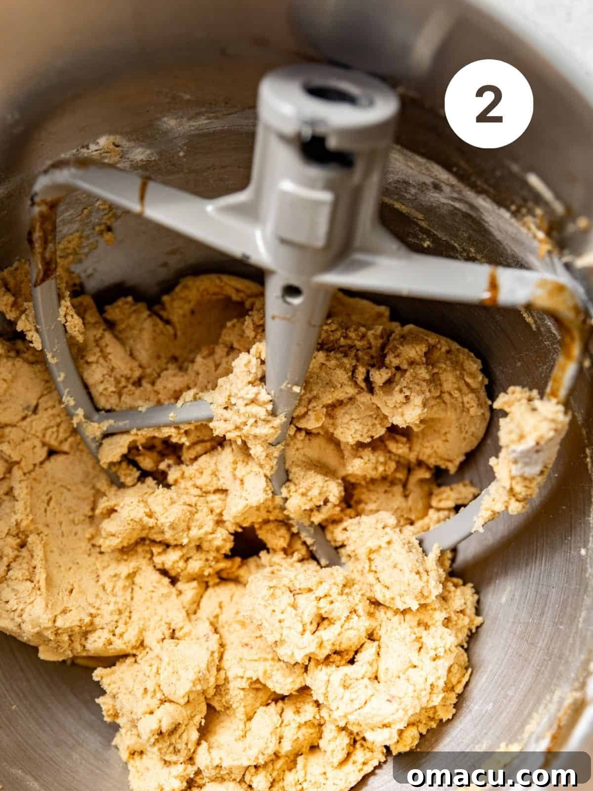 A close-up view of cookie dough in a mixing bowl, showcasing its soft and pliable texture before portioning.