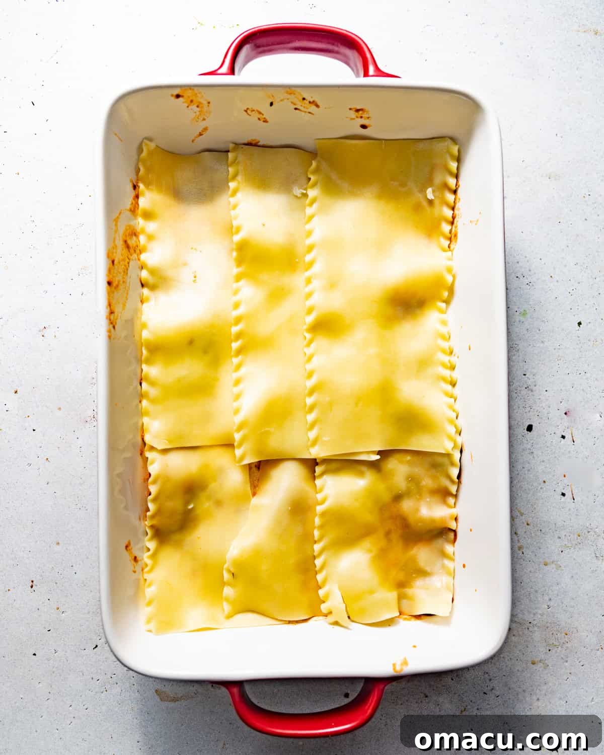 boiled lasagna noodles in a lasagna pan on top of bolognese sauce. 