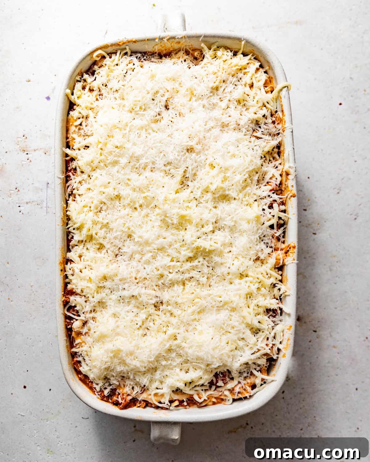 lasagna alla bolognese assembled in a baking dish with cheese on top. 