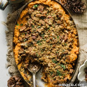 Savory sweet potato casserole in an oval casserole dish topped with a bacon and pecan breadcrumb topping.