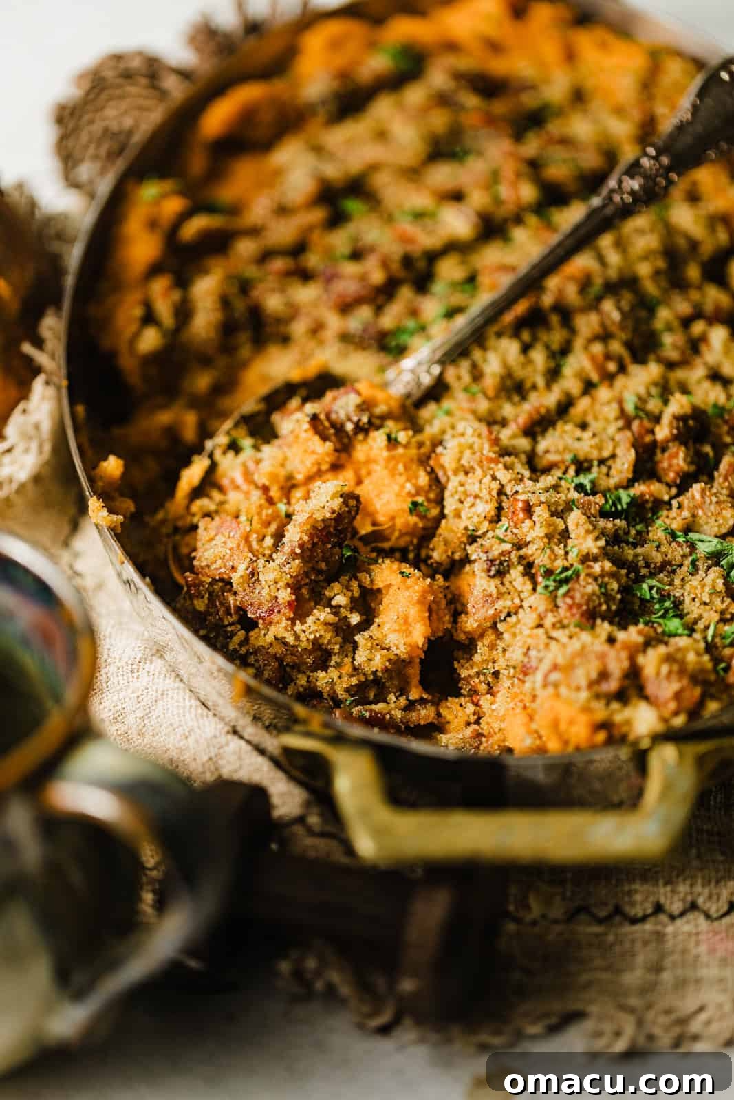 Up close photo of savory sweet potato casserole with a spoon, showing the creamy interior and crispy topping.