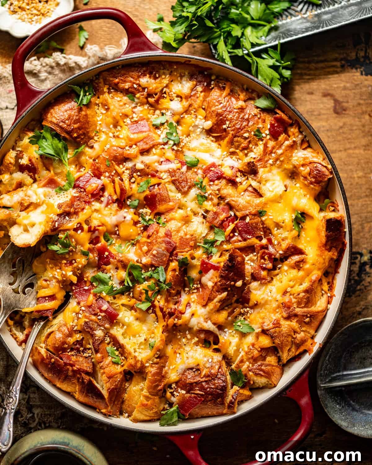 A golden-brown croissant breakfast casserole, perfectly baked in a deep round skillet and garnished with fresh parsley.