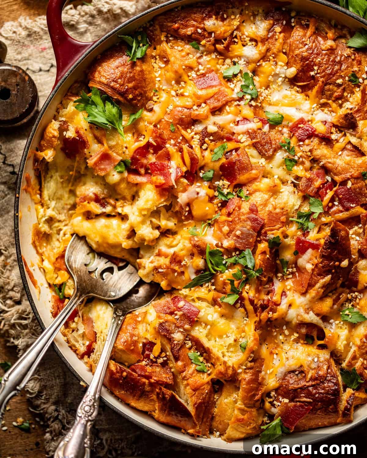 Overhead shot of a baked croissant breakfast casserole, garnished with fresh parsley and ready to be served.