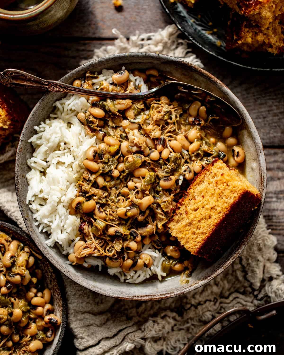 A bowl of black-eyed peas with collard greens, served with rice and a side of cornbread, showcasing a classic Southern meal.