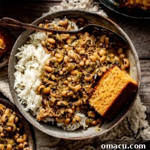 black eyed peas with collard greens in a bowl with rice and cornbread.