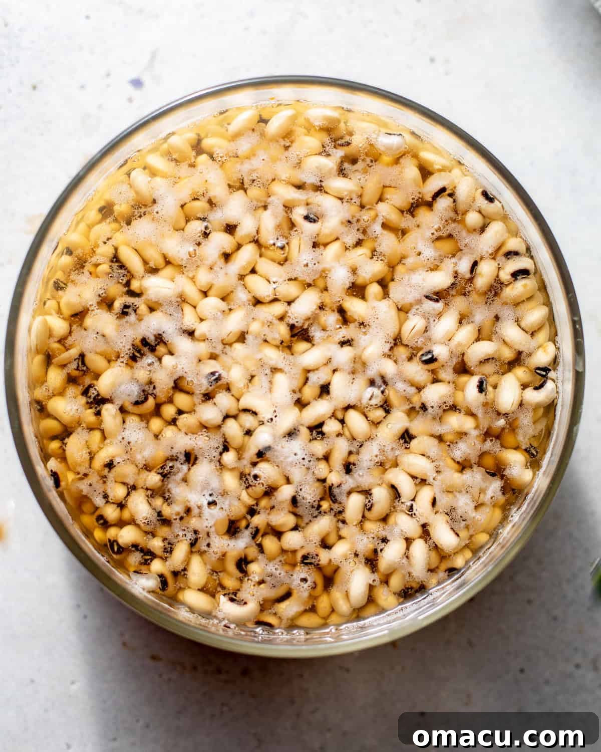 Dried black-eyed peas soaking in a bowl filled with water, ready for preparation.