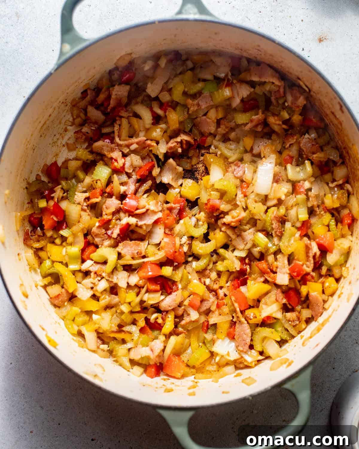 Chopped bacon, onion, bell pepper, garlic, and seasonings cooking in a Dutch oven, creating a fragrant base for the black-eyed peas.