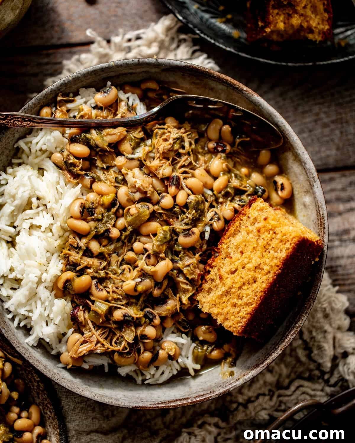 An overhead view of black-eyed peas and collard greens simmering together in a large pot, with steam rising.