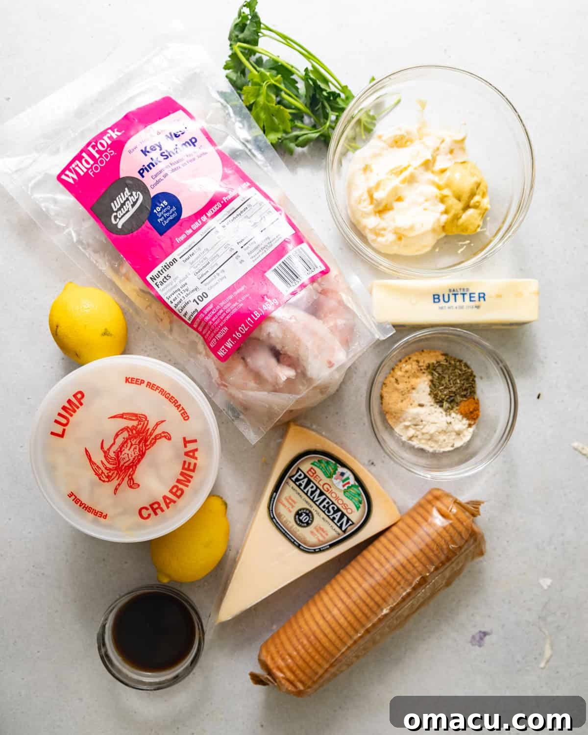 A vibrant display of fresh ingredients laid out for making crab stuffed shrimp, including plump shrimp, lump crab meat, various seasonings, and fresh herbs.