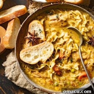 Up close photo of creamy Dutch oven chicken noodle soup in a bowl with bread, showcasing its rich texture.