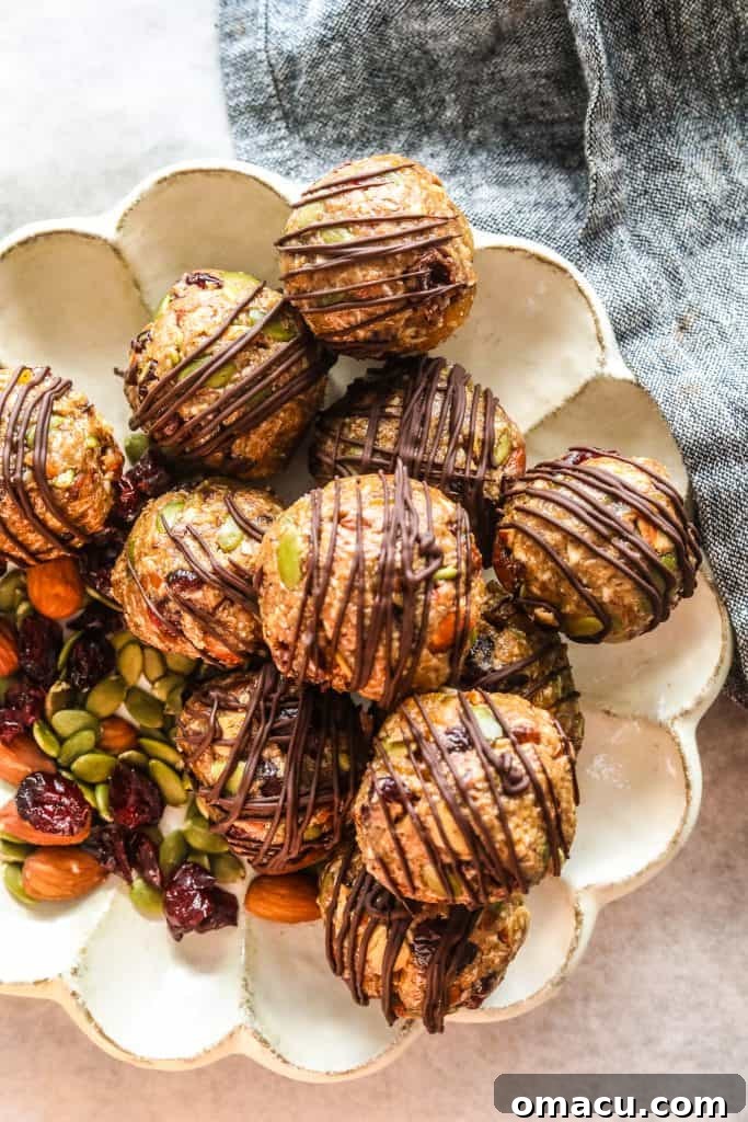 Close-up of golden no-bake energy bites, some with a delicate drizzle of dark chocolate, highlighting their appetizing texture.