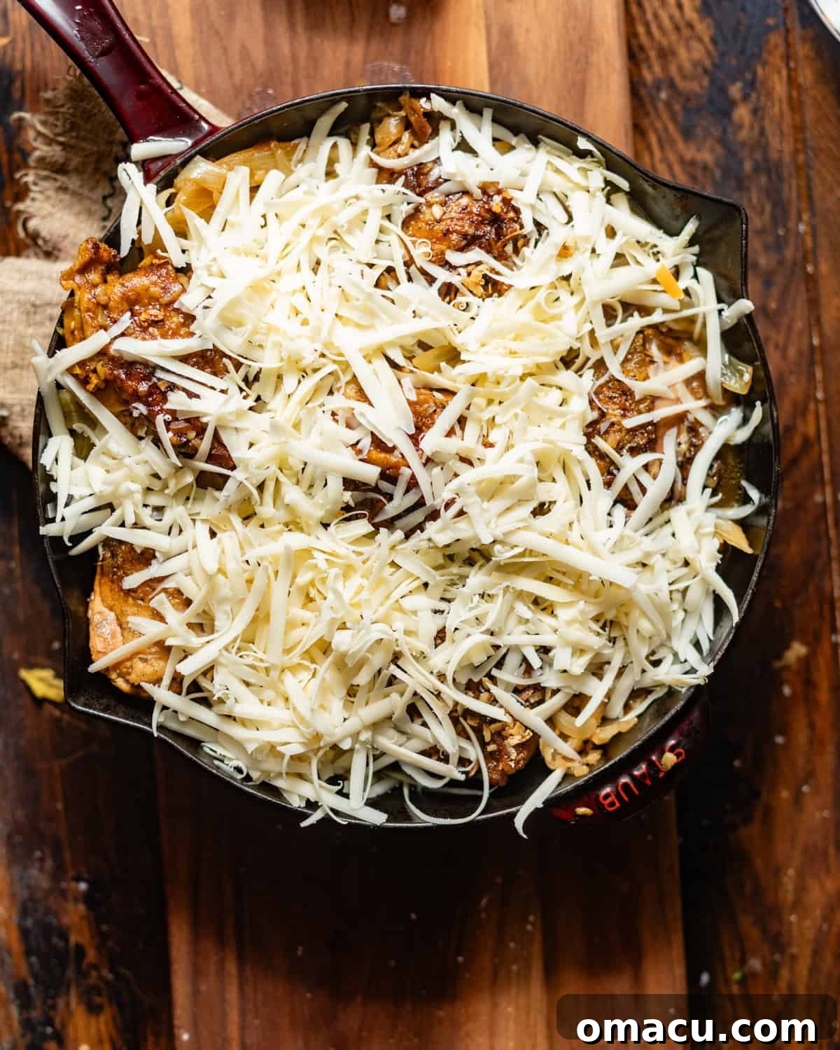 french onion chicken in a skillet topped with gruyere cheese.