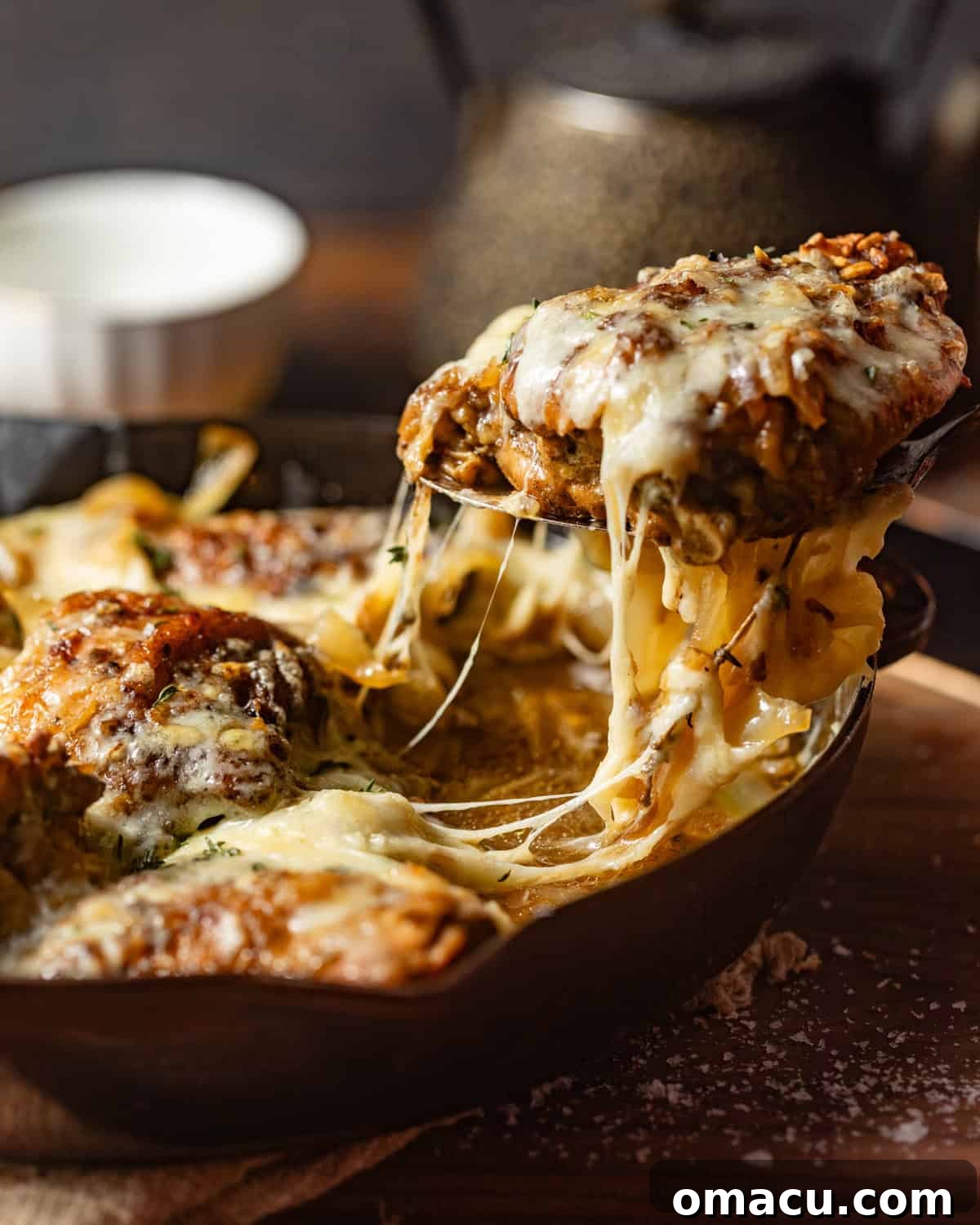 slow cooker french onion chicken being pulled out of the pan with a serving spoon.