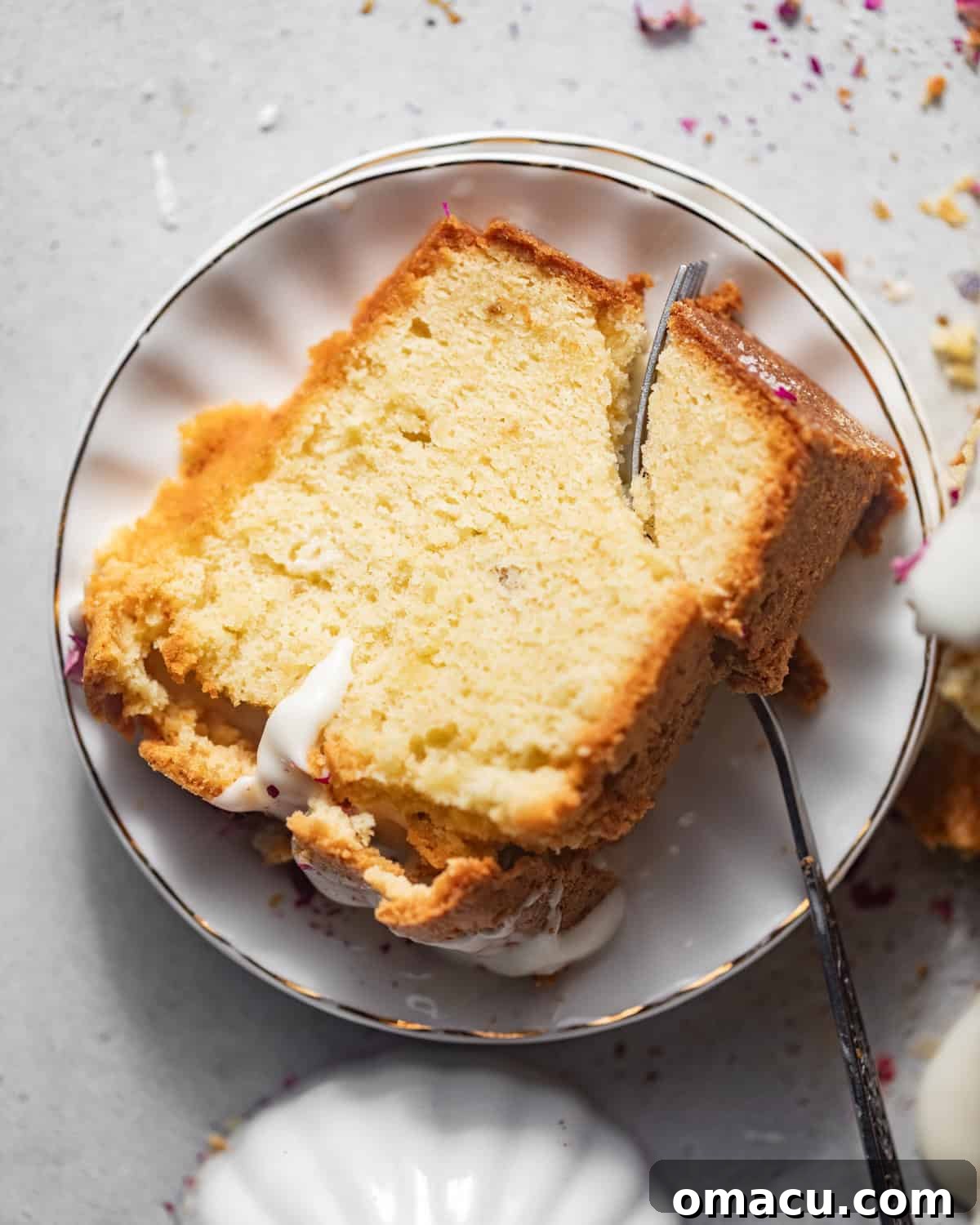 A solitary slice of cream cheese pound cake elegantly placed on a white plate, accompanied by a fork, inviting a delightful taste.