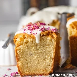 a slice of cream cheese pound cake on a white surface with rose petals on top.