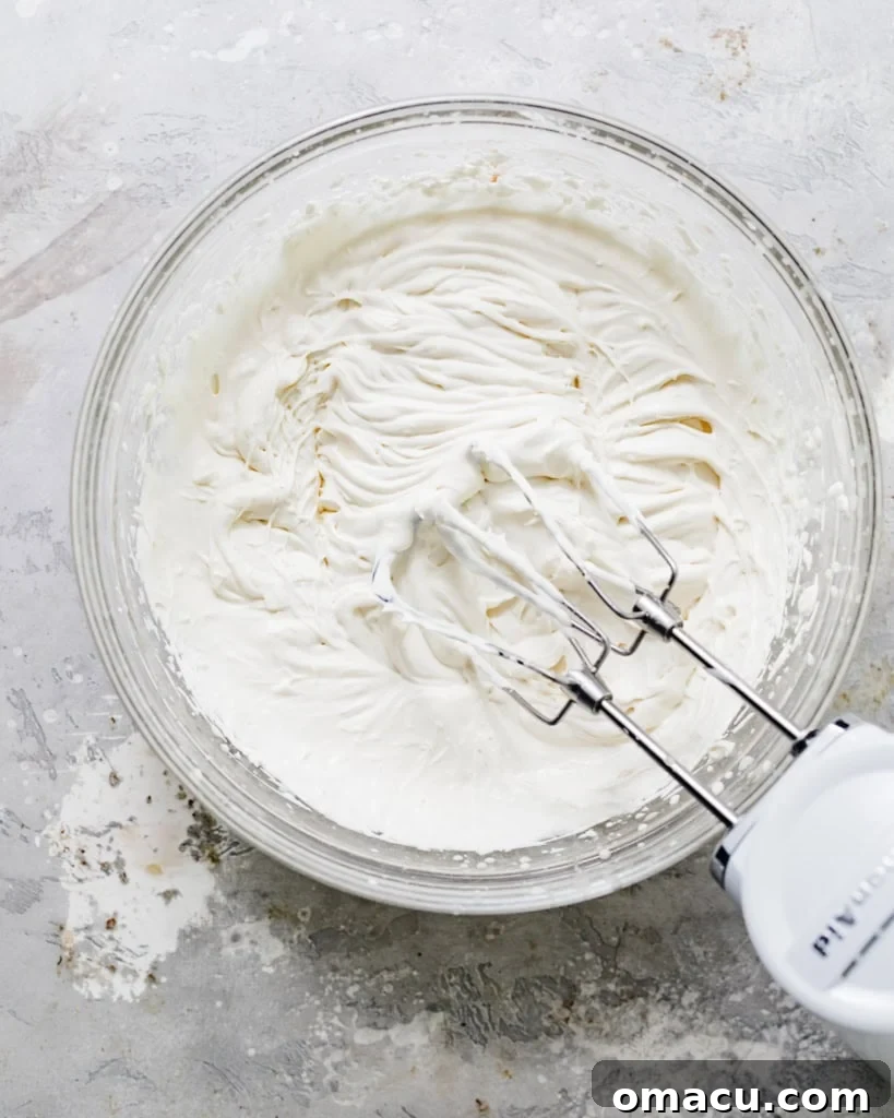 Cold heavy cream and sour cream whipped together in a separate mixing bowl, reaching stiff peaks.