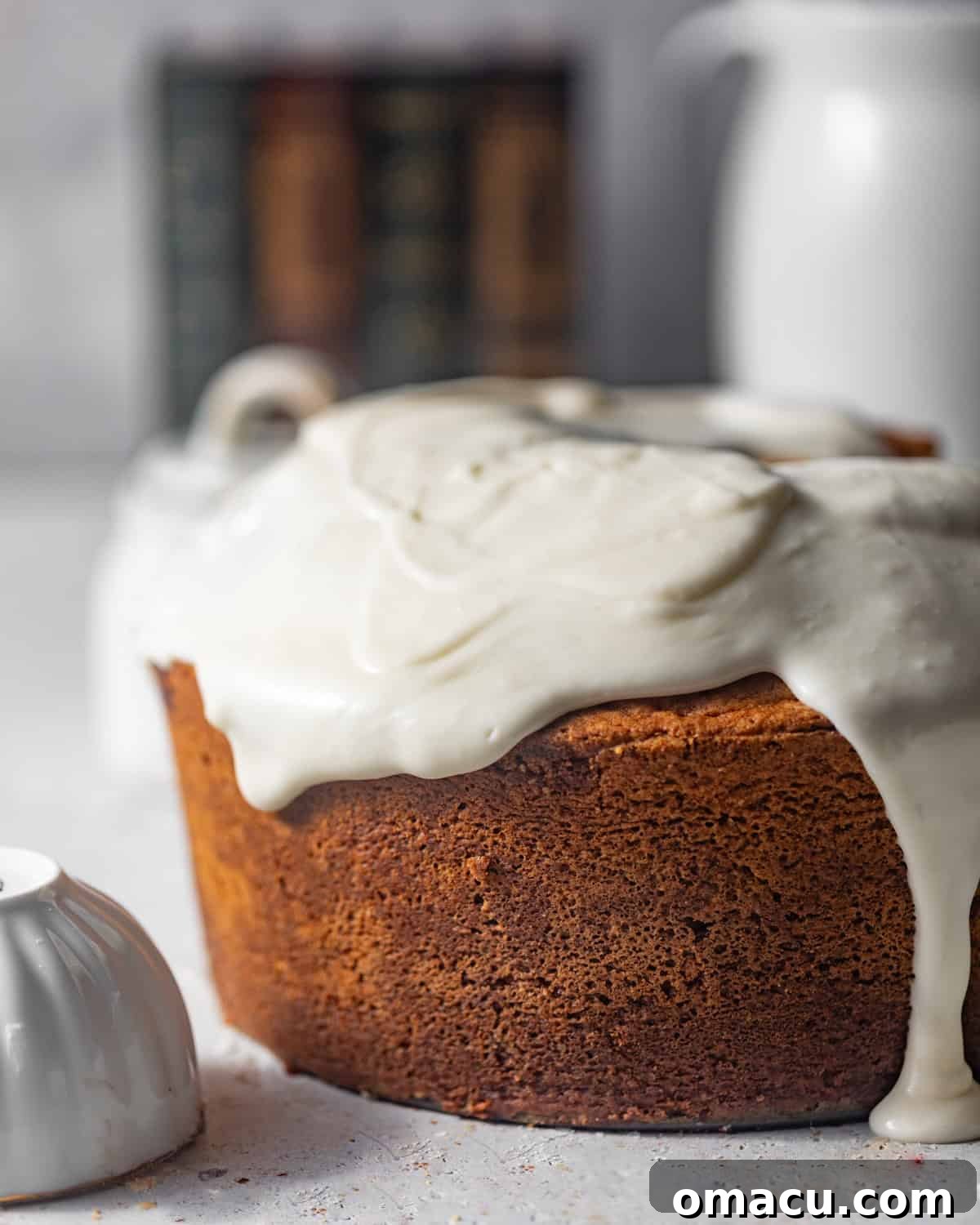A delectable cream cheese pound cake generously drizzled with a smooth, white cream cheese glaze on a decorative plate.