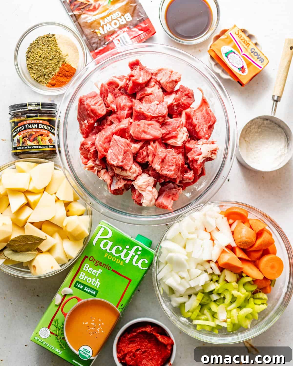 Small bowls displaying individual ingredients laid out on a white surface, ready to be used for making stovetop beef stew.