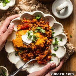 cornbread cowboy casserole in a bowl with hands holding the bowl.