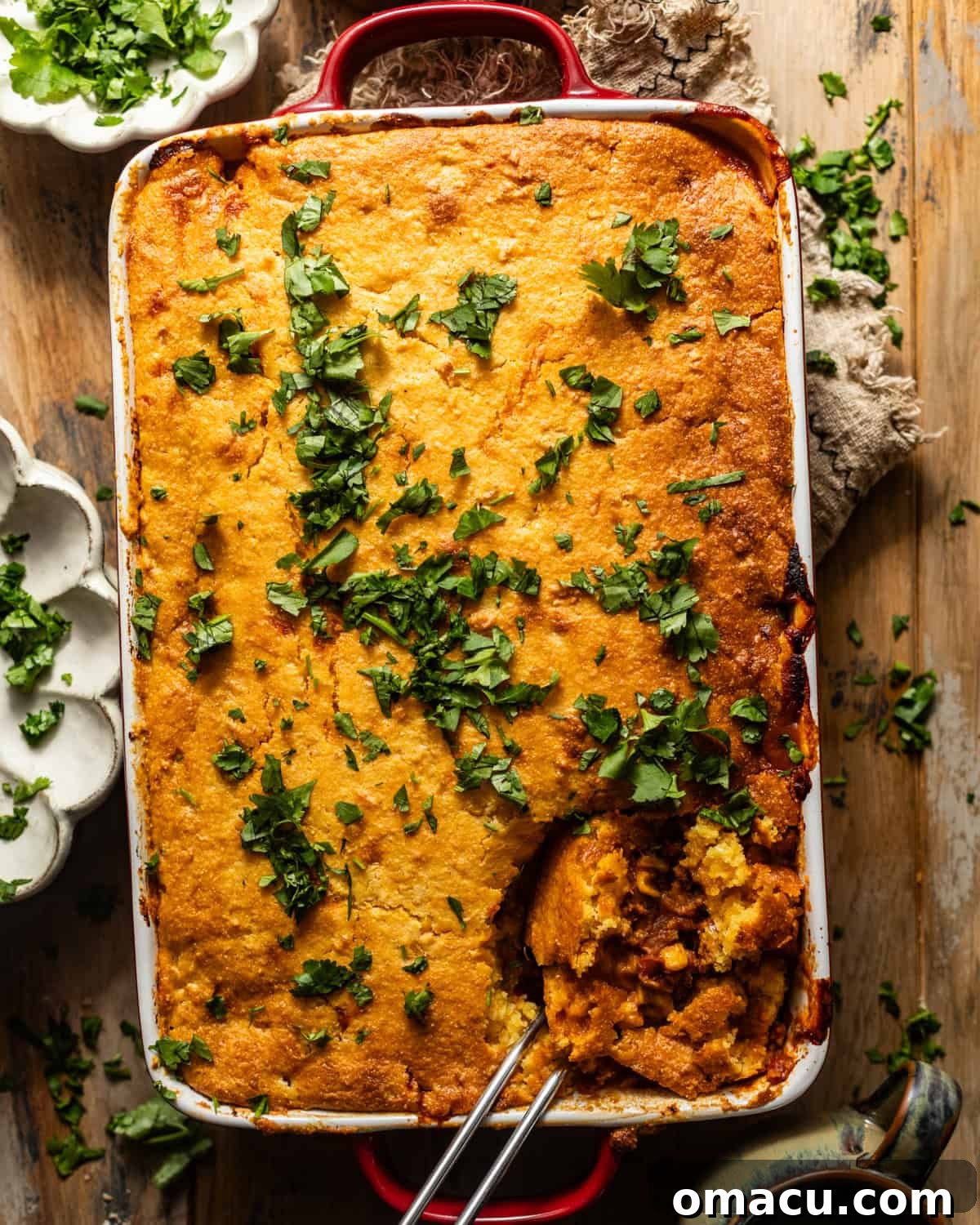 A freshly baked cornbread cowboy casserole in a baking pan, garnished with fresh parsley for a vibrant finish.