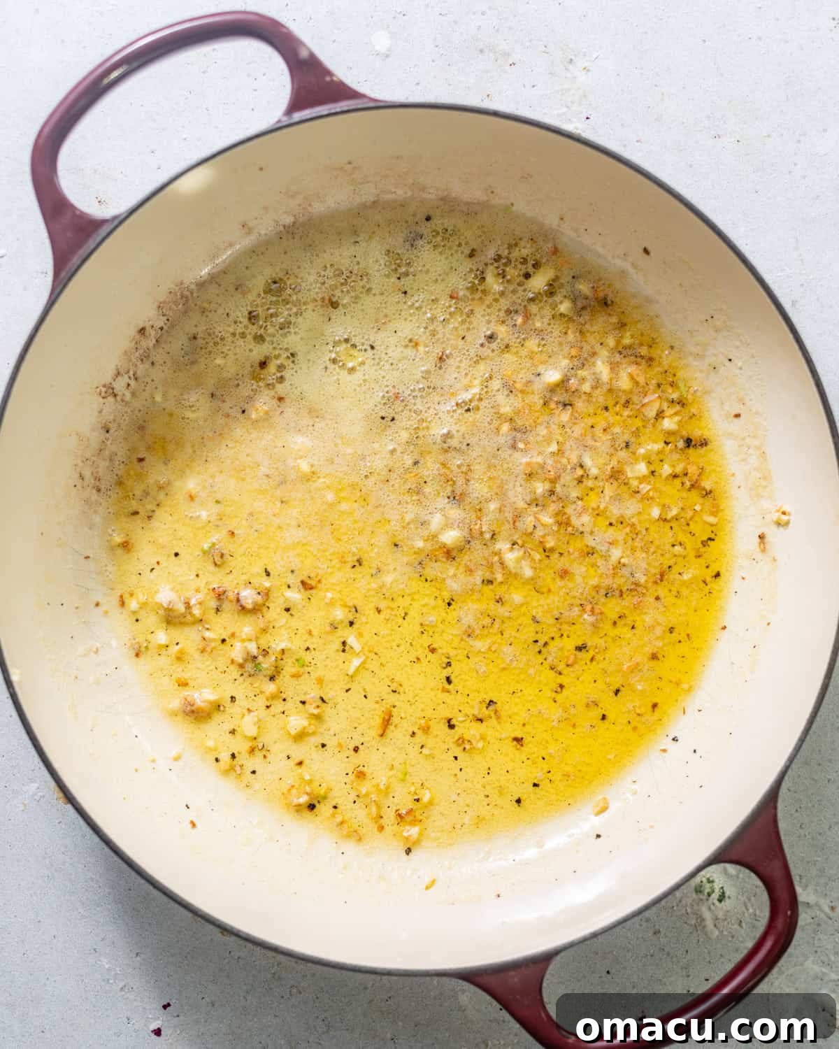 Melted butter, minced garlic, and drained capers simmering in a large skillet, creating a fragrant base.