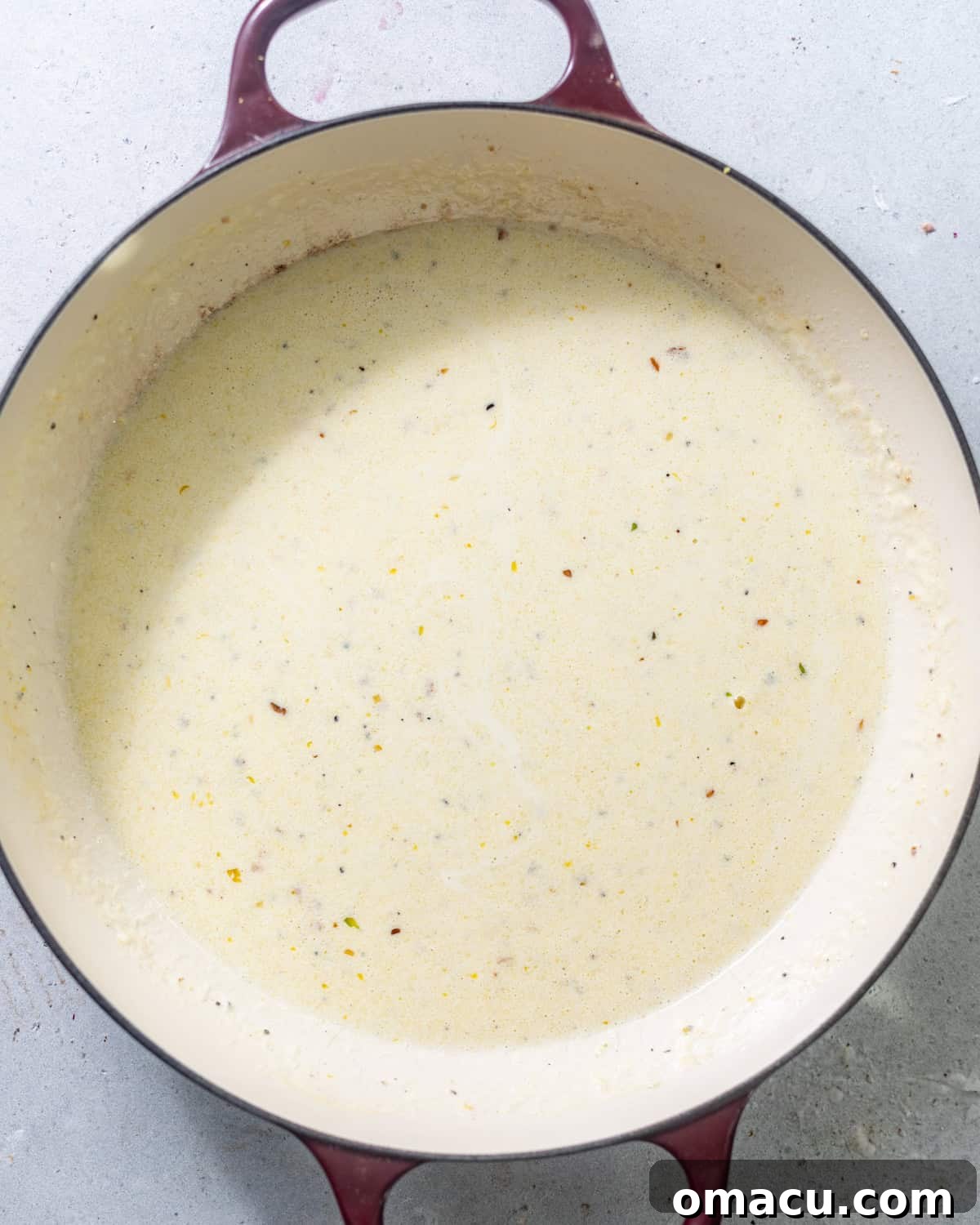 Close-up of a creamy lemon caper sauce simmering gently in a large skillet, ready for the pasta.