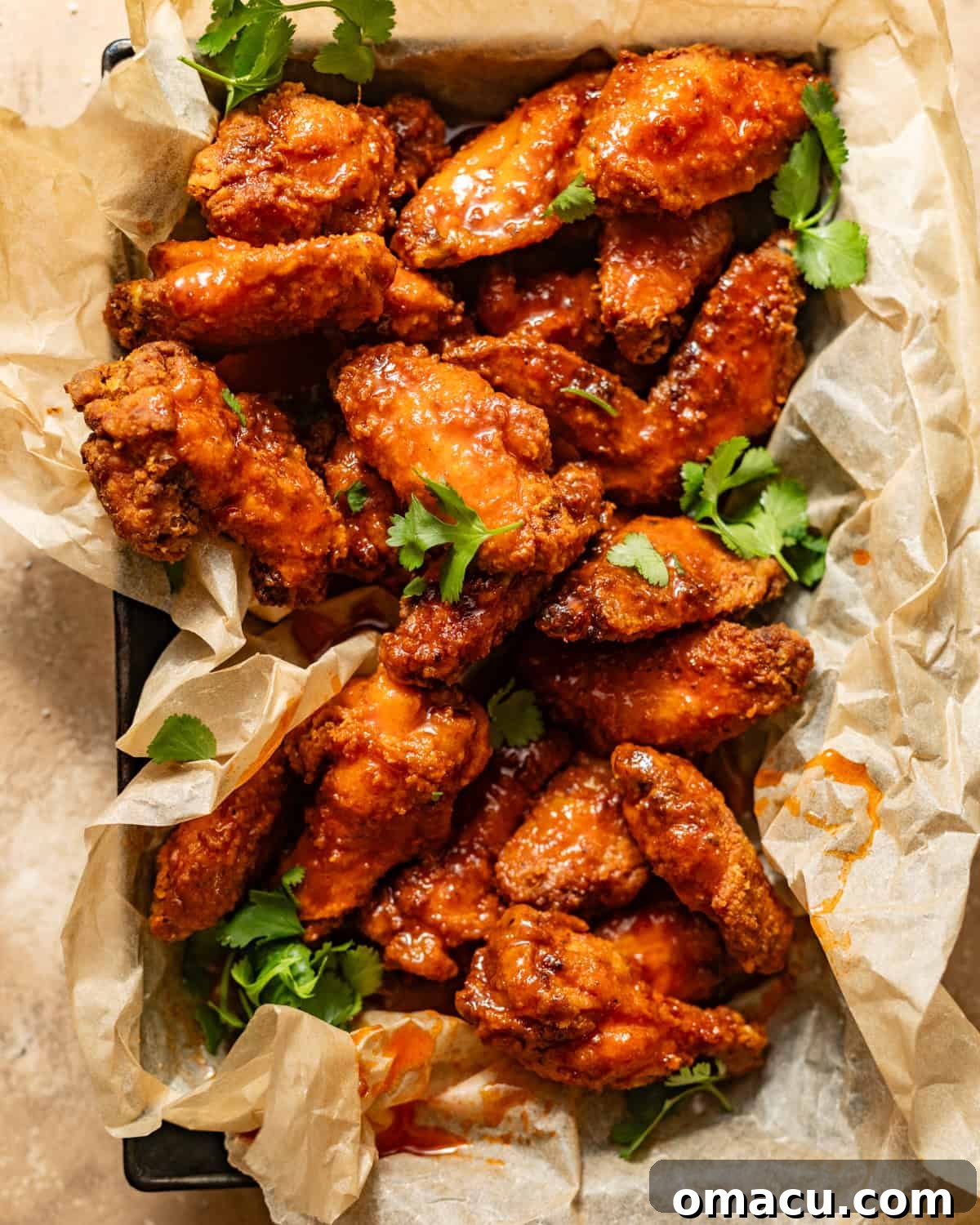 Basket of golden-brown hot honey chicken wings garnished with fresh parsley.