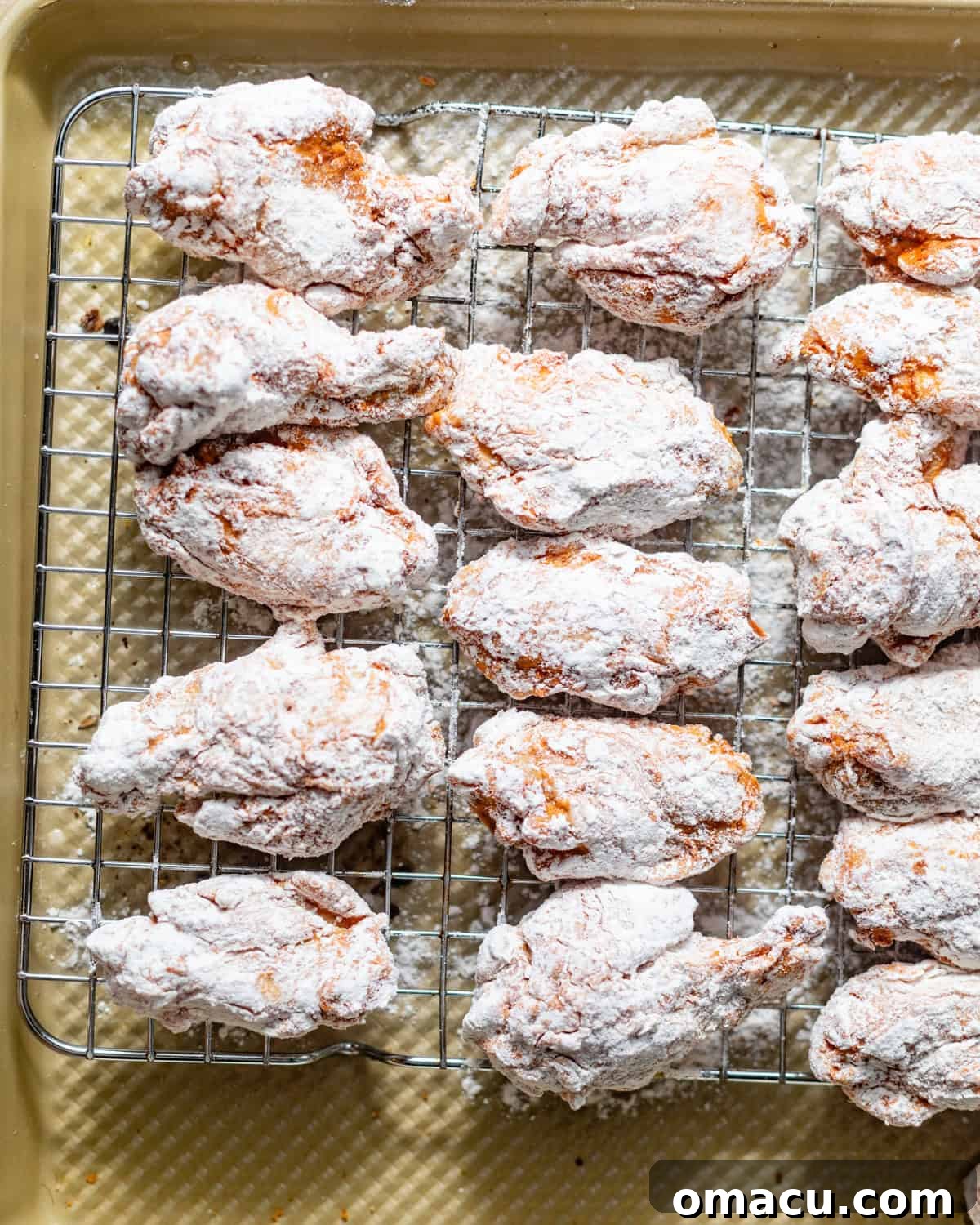 Coated chicken wings resting on a wire rack to set the dredge.