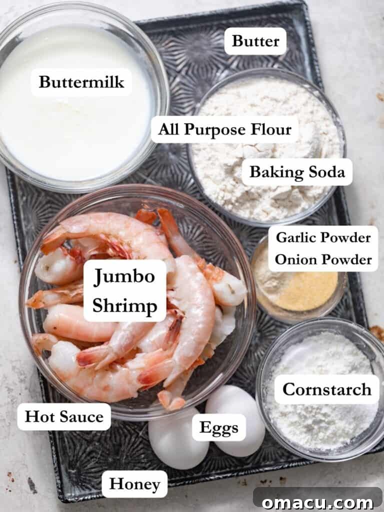Ingredients laid out for buffalo shrimp: jumbo shrimp, flour, spices, hot sauce, butter, baking soda, eggs, cornstarch, and honey.