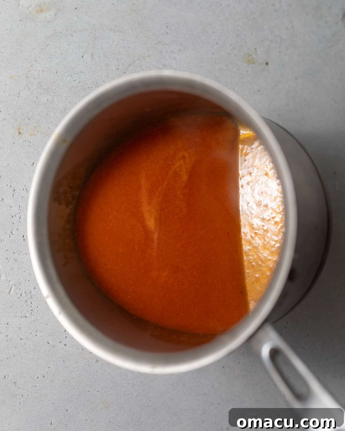 Homemade buffalo sauce simmering in a saucepan.