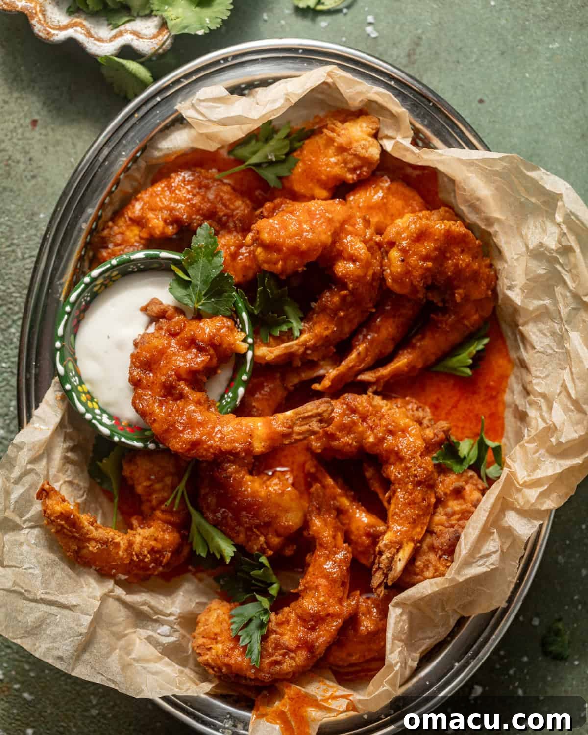 Overhead shot of buffalo shrimp covered in sauce on a serving tray.