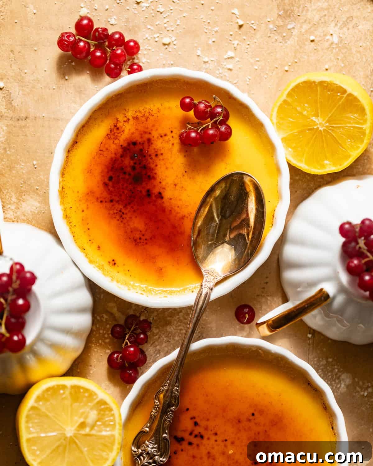Exquisite lemon creme brulee in individual ramekins, garnished with vibrant red currants, ready to be enjoyed.