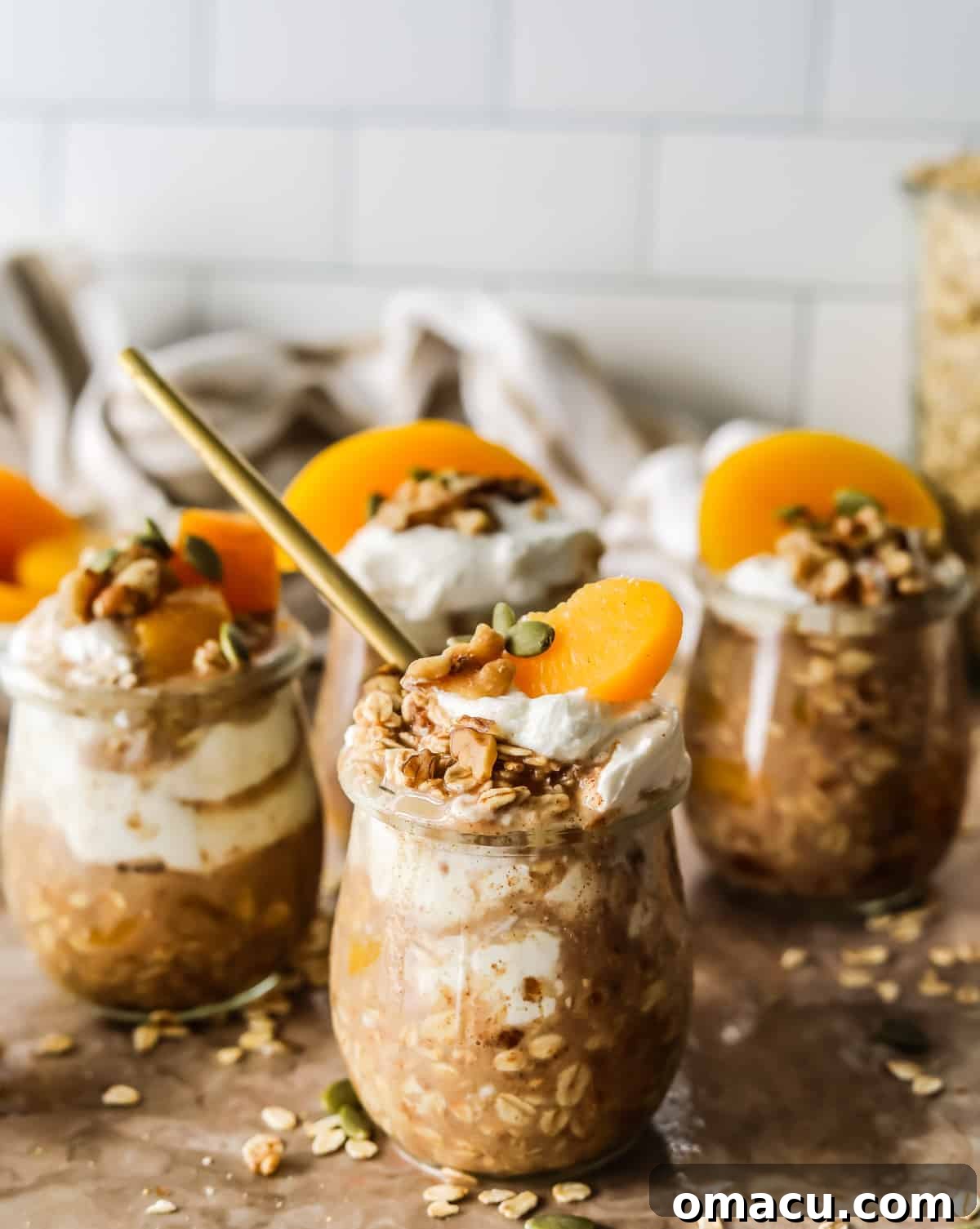 A top-down view of Peach Cobbler Overnight Oats in a glass jar, showing layers of oats and peaches.