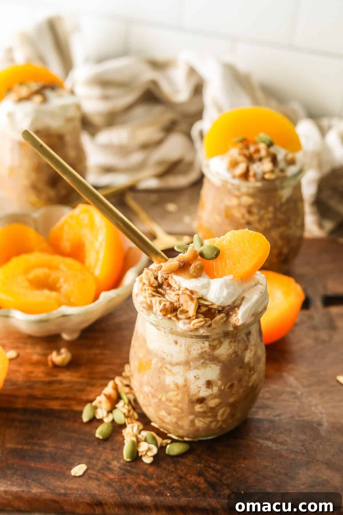 Various Peach Cobbler Overnight Oats jars topped with fresh fruit and nuts.