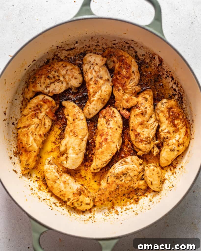 Chicken tenderloins cooking in a large pot until golden brown.