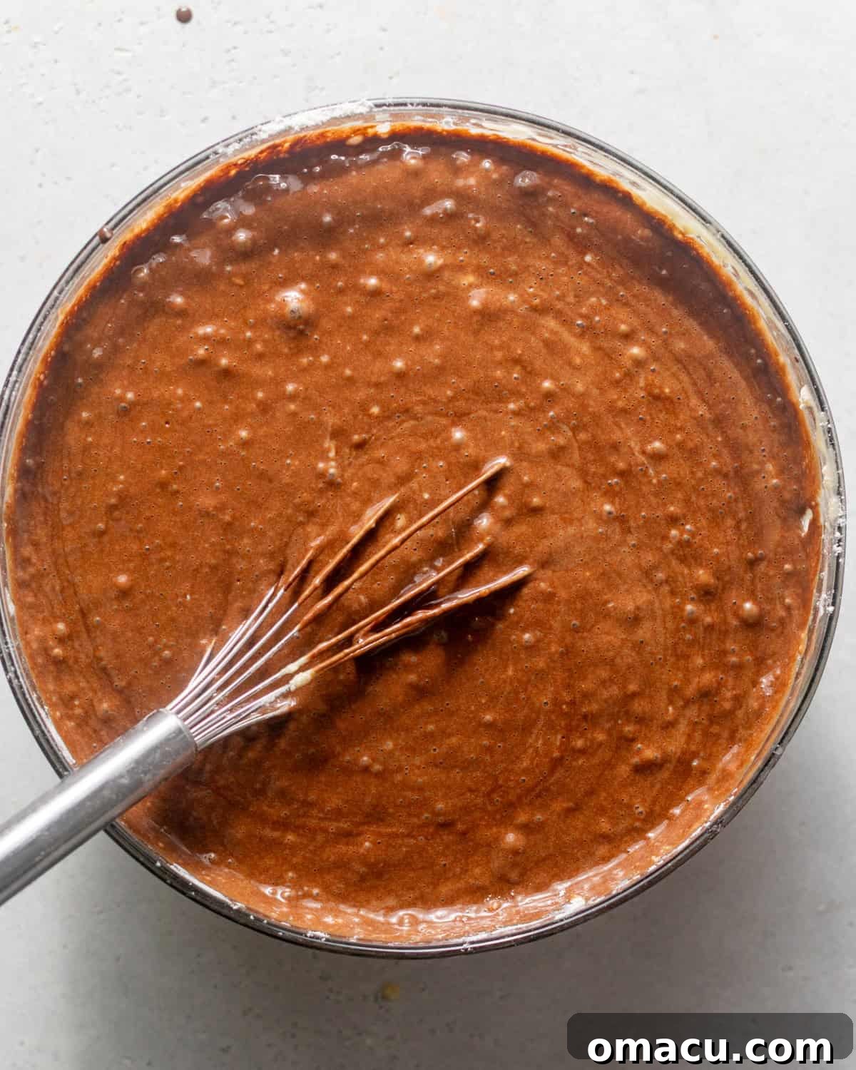 Chocolate mud cake batter in a mixing bowl with a whisk, ready for baking.