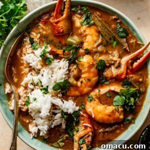 Close-up photo of a rich Cajun seafood gumbo in a bowl, showing shrimp, crab, and sausage.