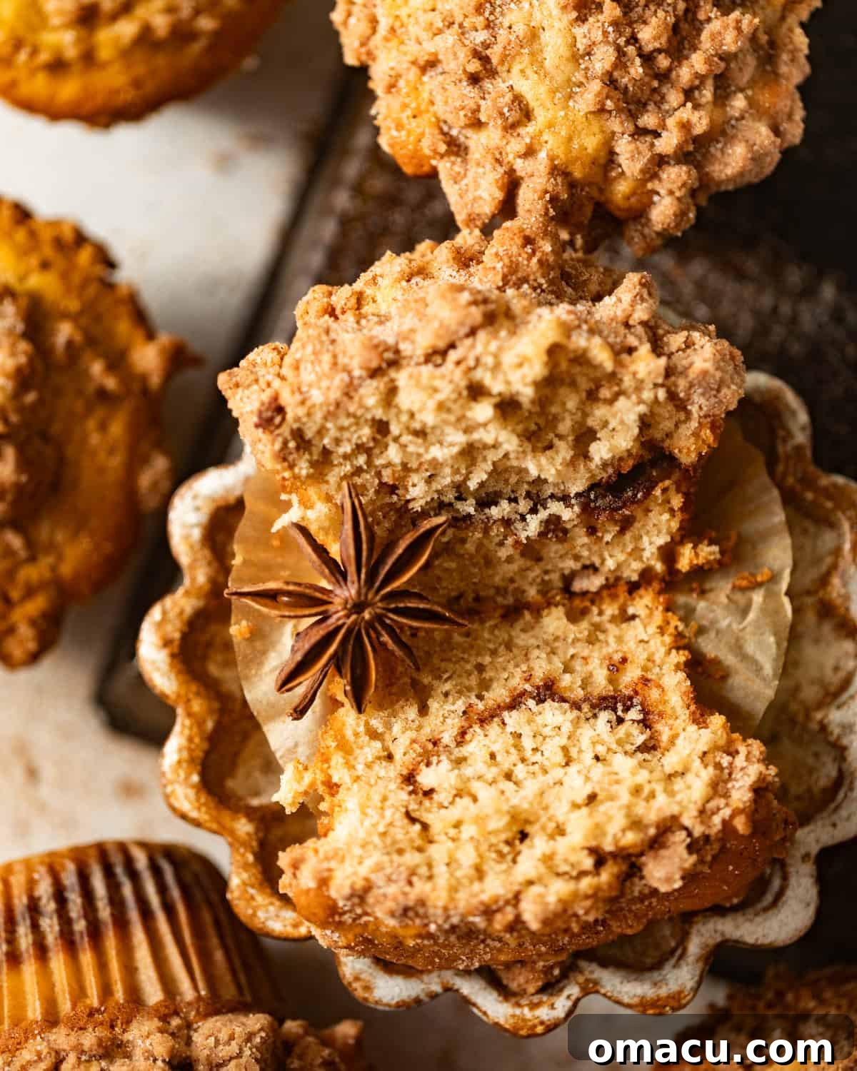 A coffee cake muffin cut in half to showcase the beautiful cinnamon sugar swirl through its center.