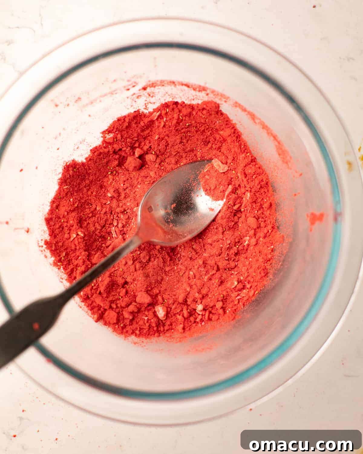 Freeze-dried strawberries blended into a fine, vibrant pink powder in a bowl, ready for frosting.