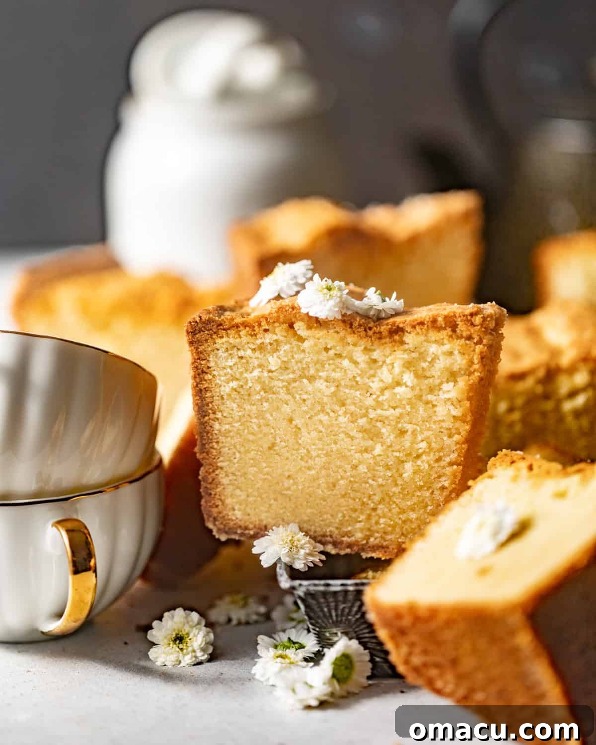 slices of white chocolate pound cake on a white surface garnished with edible flowers.