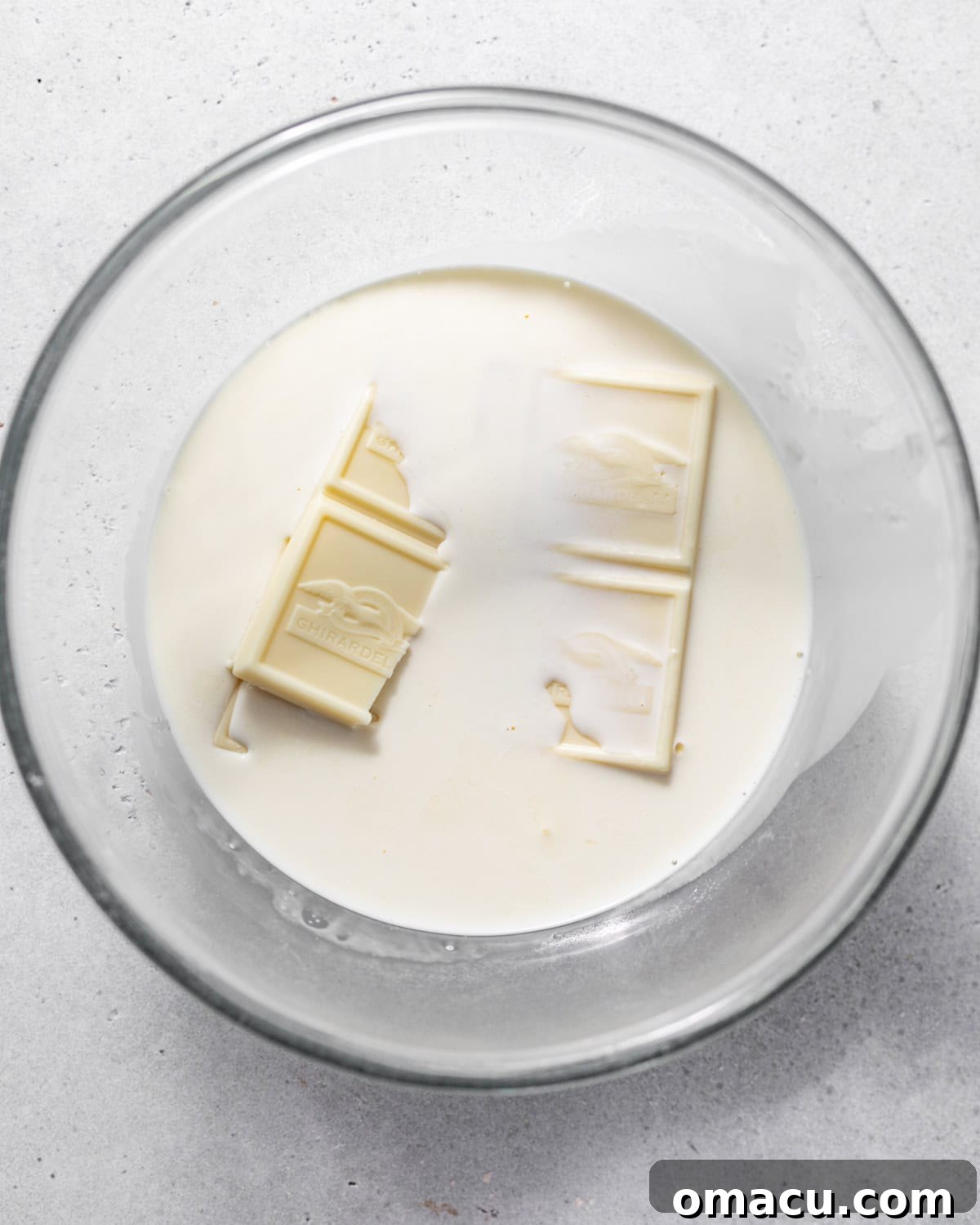 white chocolate squares and warm heavy cream in a bowl.