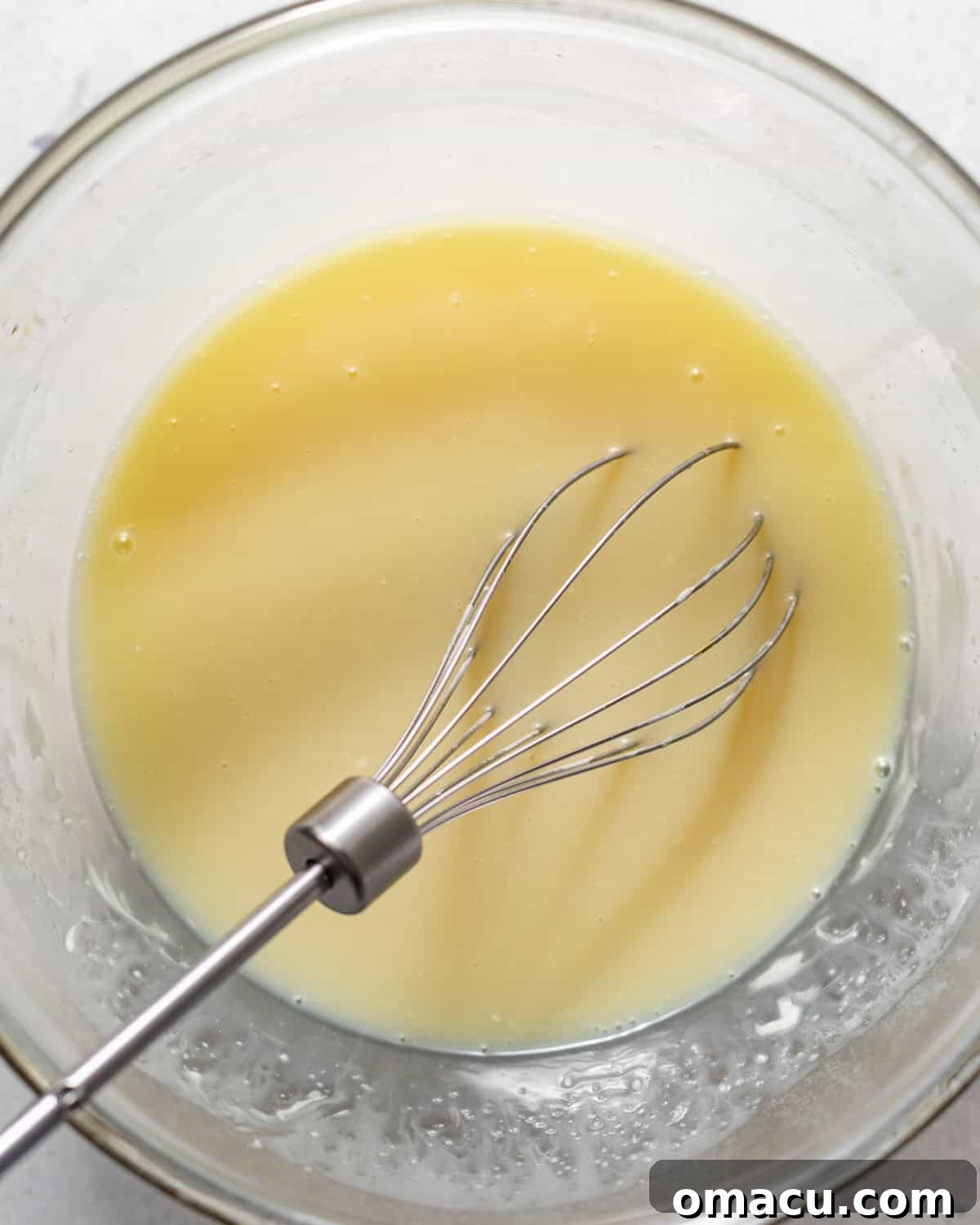 white chocolate ganache in a bowl with a whisk.