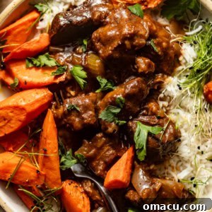 up close photo of beef tips and gravy on a plate with rice and carrots.