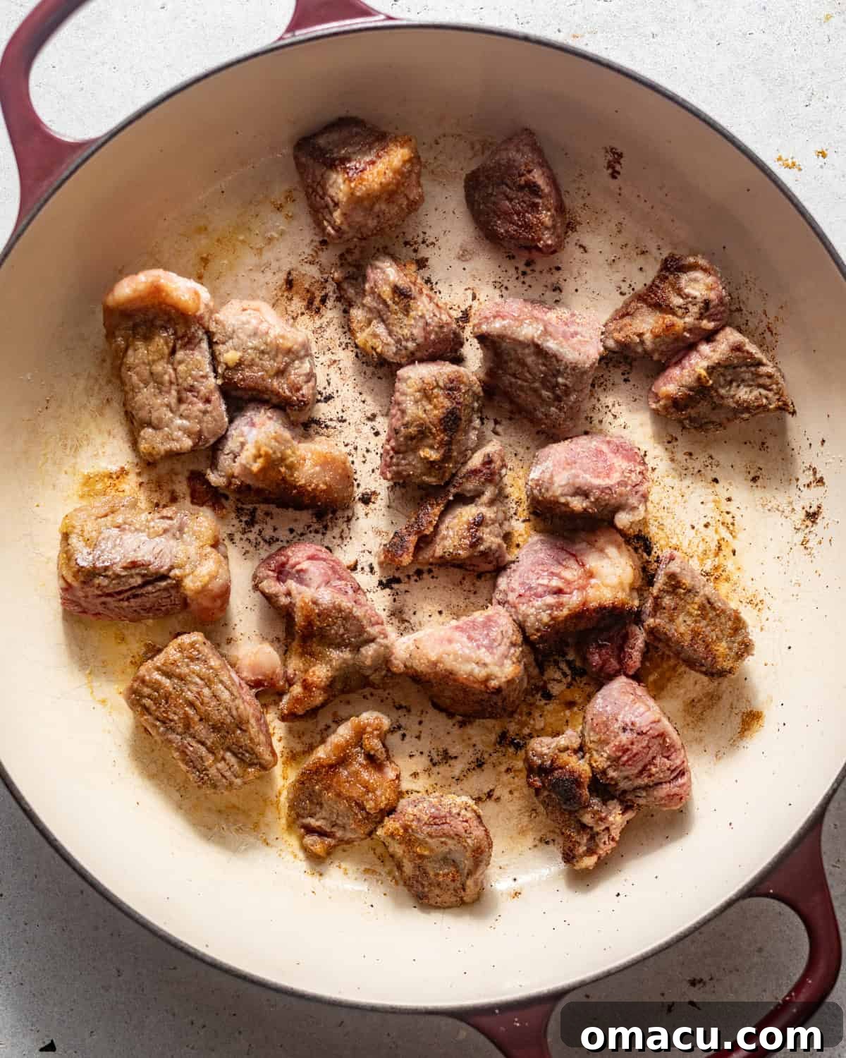 Seared beef tips browning in a large Dutch oven or pot.