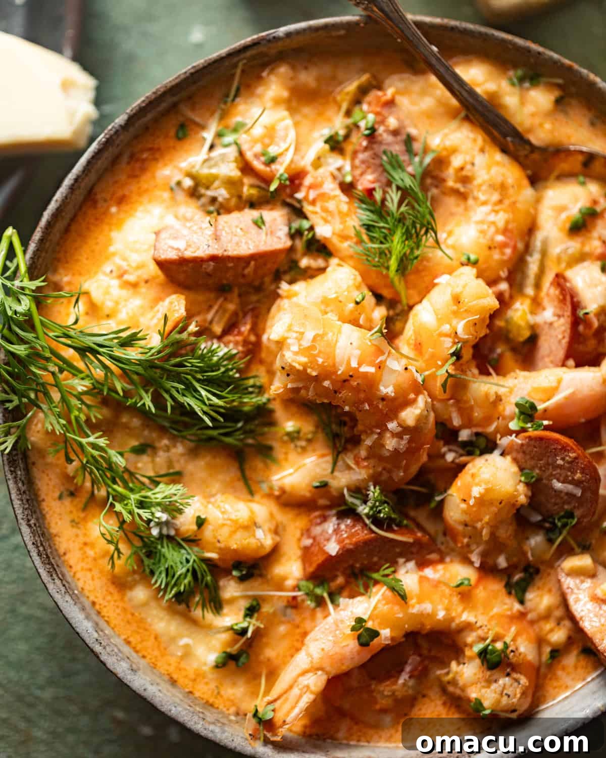 Close-up photo of Cajun shrimp and grits in a bowl with a spoon, garnished beautifully.
