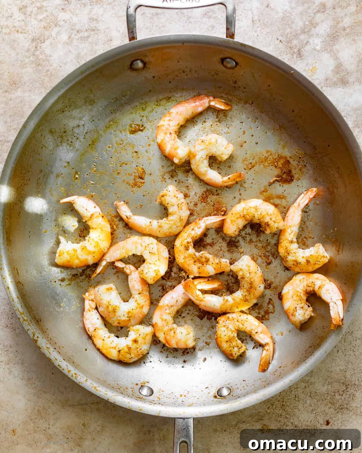 Perfectly seared, pink shrimp in a skillet, showcasing their delicious golden-brown crust.